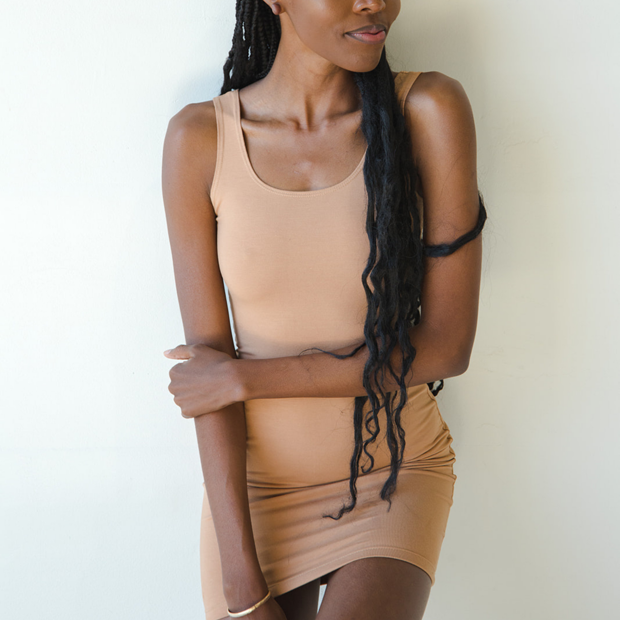 Product shot of NŪD Apparel Tayler Slip Dress, wide strap, fitted style and seamless, made of bamboo fabric produced in California, in Medium Nude on dark-skinned model, front shot