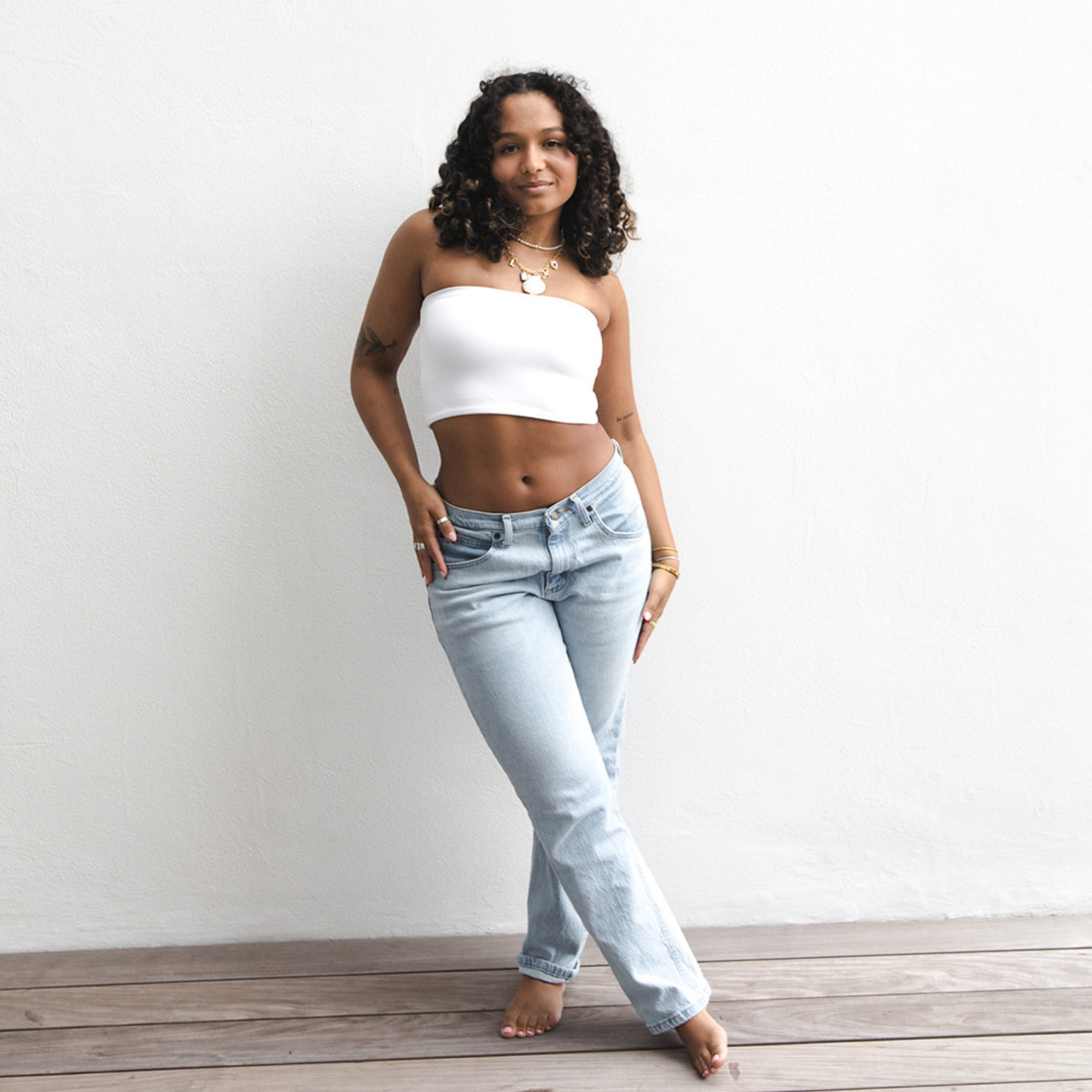 Product shot of NŪD Apparel Hunter Double-Layered Bandeau, strapless, cropped and seamless style, made of bamboo fabric produced in California, in White on medium-skinned model paired with light-wash jeans, front shot