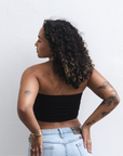 Product shot of NŪD Apparel Hunter Double-Layered Bandeau, strapless, cropped and seamless style, made of bamboo fabric produced in California, in Black on medium-skinned model paired with light-wash jeans, back shot