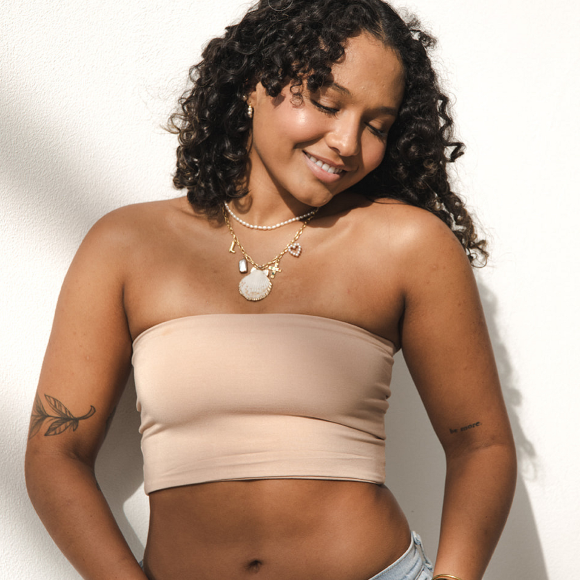 Product shot of NŪD Apparel Hunter Double-Layered Bandeau, strapless, cropped and seamless style, made of bamboo fabric produced in California, in Light Nude on medium-skinned model paired with light-wash jeans