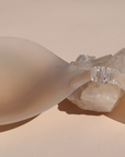 Product shot of reusable and sticky Light tint Silicone Stick-on Bra laying against silica crystal and light pink background, close-up shot showing the clasp and razor thin edges of the Silicone Stick-on Bra