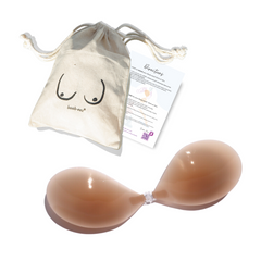 Product shot of reusable and sticky Medium Tint Silicone Stick-on Bra with a branded drawstring unbleached cotton muslin pouch packaging and information insert card with wear and care instructions, showing thin edge of the Silicone Stick-on Bra