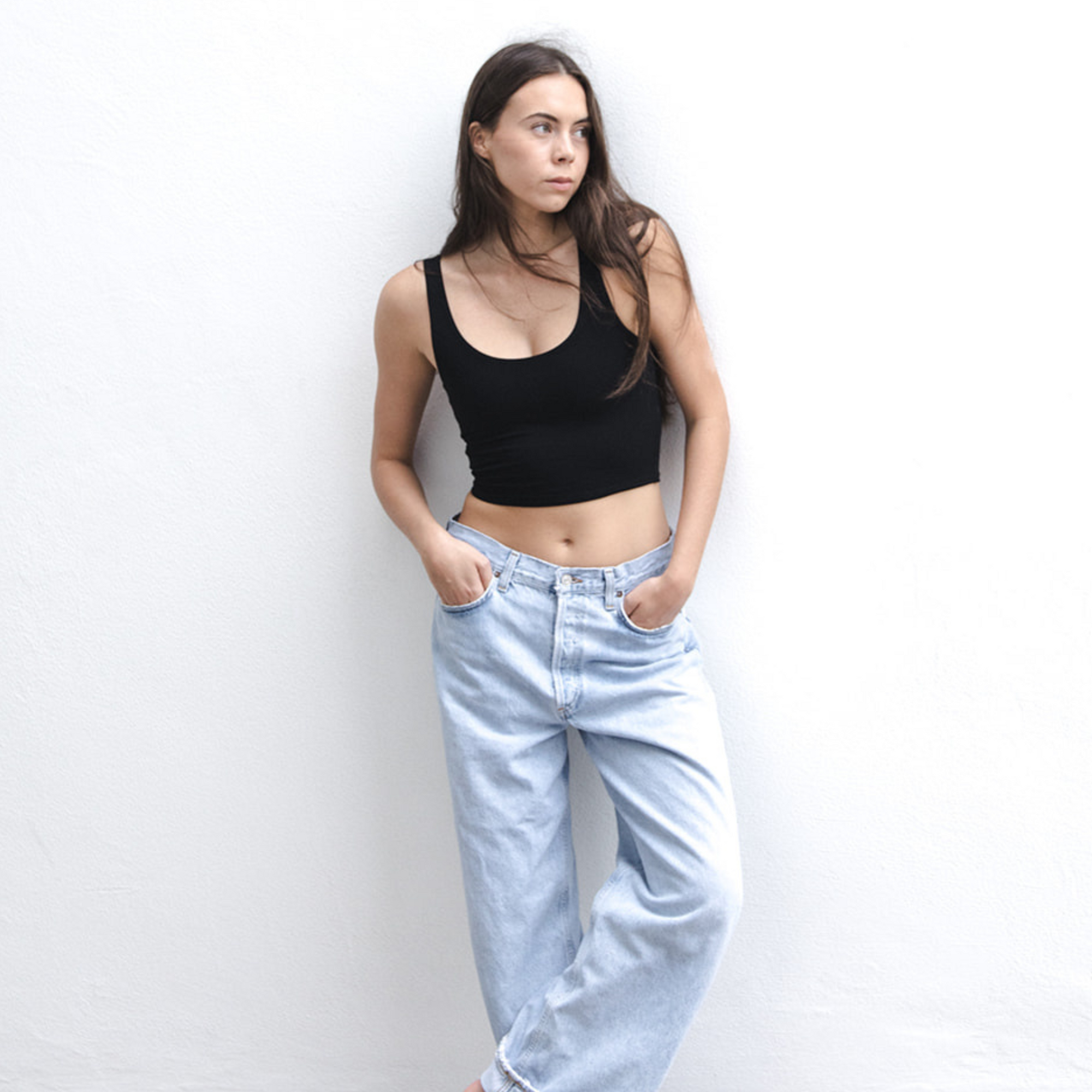 Product shot of NŪD Apparel Devon Double Layered Scoop Crop top, wide strap and seamless, made of bamboo fabric produced in California, in Black on fair-skinned model paired with light-wash jeans, front wide shot