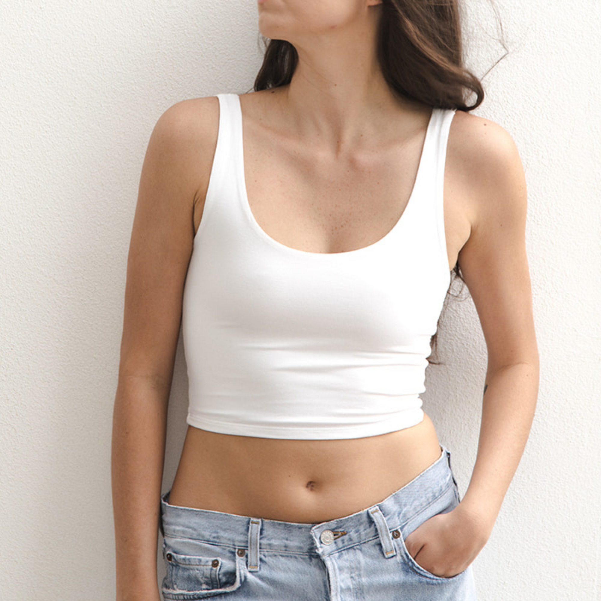 Product shot of NŪD Apparel Devon Double Layered Scoop Crop top, wide strap and seamless, made of bamboo fabric produced in California, in White on fair-skinned model paired with light-wash jeans, front shot