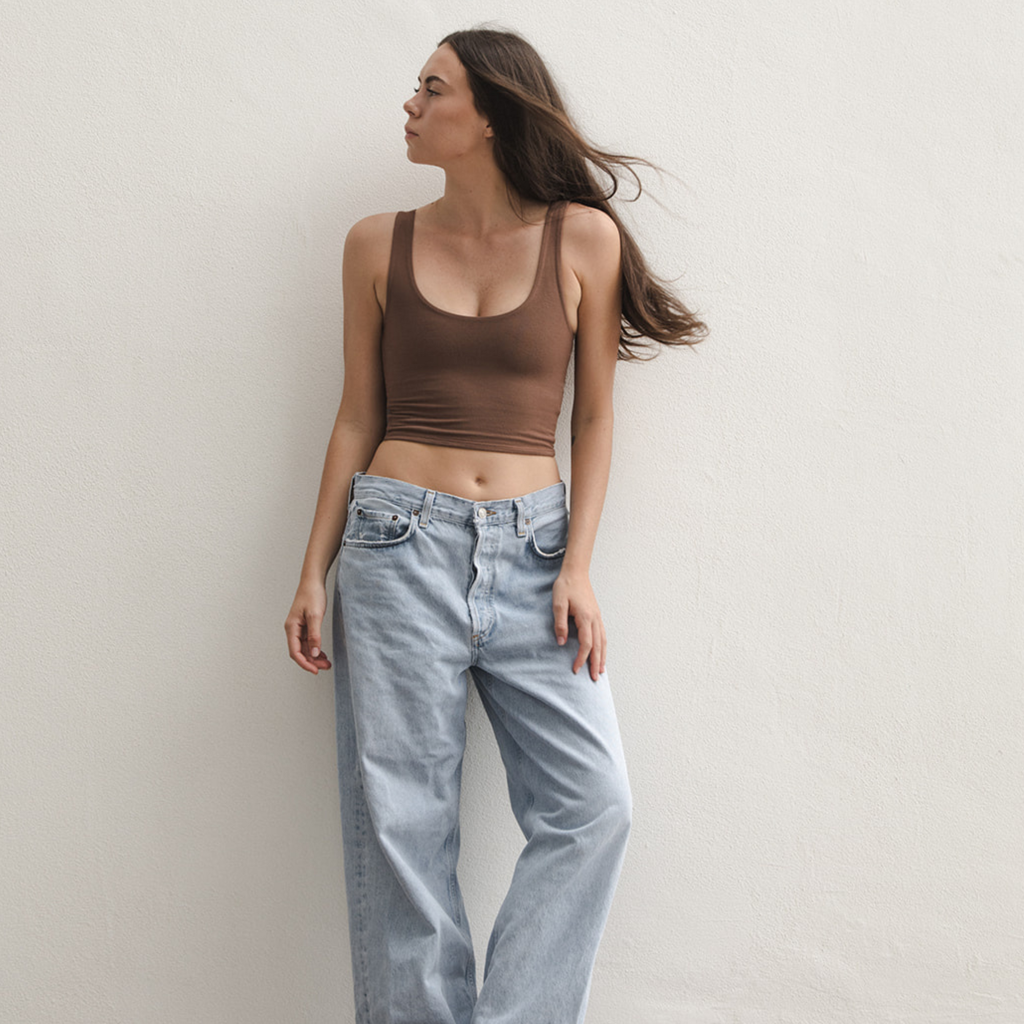 Product shot of NŪD Apparel Devon Double Layered Scoop Crop top, wide strap and seamless, made of bamboo fabric produced in California, in Dark Nude on fair-skinned model paired with light-wash jeans, front wide shot