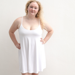 Product shot of NŪD Apparel Betty Swinging Slip Dress, thin adjustable strap, loose style and with shelf bra, made of bamboo fabric produced in California, in White on fair-skinned model, front shot