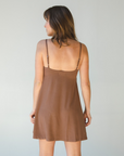 Product shot of NŪD Apparel Betty Swinging Slip Dress, thin adjustable strap, loose style and with shelf bra, made of bamboo fabric produced in California, in Dark Nude on fair-skinned model, back shot
