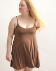 Product shot of NŪD Apparel Betty Swinging Slip Dress, thin adjustable strap, loose style and with shelf bra, made of bamboo fabric produced in California, in Dark Nude on fair-skinned model, front shot
