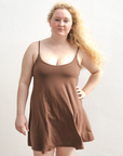 Product shot of NŪD Apparel Betty Swinging Slip Dress, thin adjustable strap, loose style and with shelf bra, made of bamboo fabric produced in California, in Dark Nude on fair-skinned model, front shot