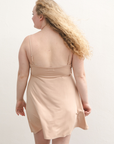 Product shot of NŪD Apparel Betty Swinging Slip Dress, thin adjustable strap, loose style and with shelf bra, made of bamboo fabric produced in California, in Light Nude on fair-skinned model, back shot