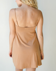 Product shot of NŪD Apparel Betty Swinging Slip Dress, thin adjustable strap, loose style and with shelf bra, made of bamboo fabric produced in California, in Medium Nude on fair-skinned model, back shot