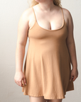 Product shot of NŪD Apparel Betty Swinging Slip Dress, thin adjustable strap, loose style and with shelf bra, made of bamboo fabric produced in California, in Medium Nude on fair-skinned model, front shot