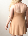 Product shot of NŪD Apparel Betty Swinging Slip Dress, thin adjustable strap, loose style and with shelf bra, made of bamboo fabric produced in California, in Medium Nude on fair-skinned model, back shot