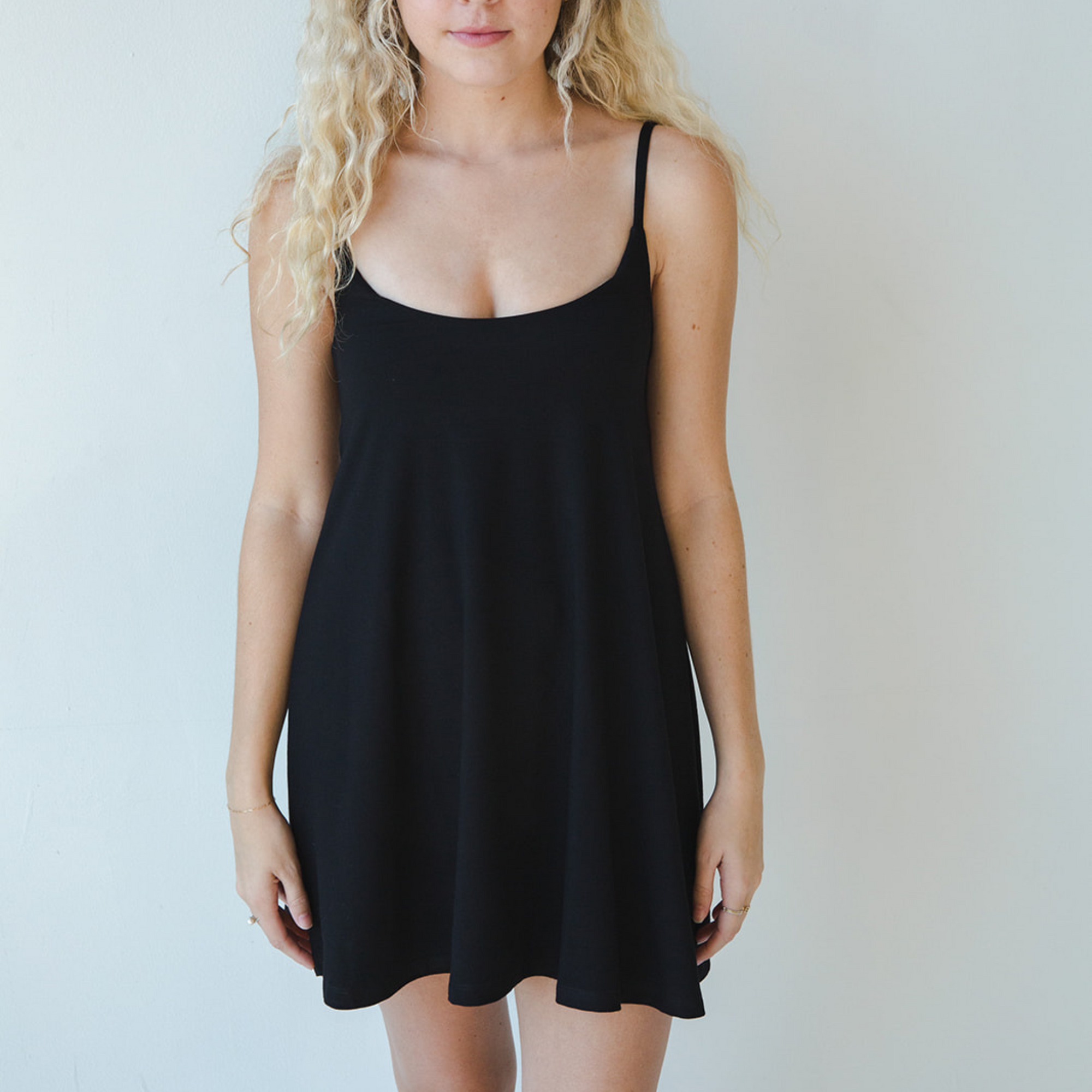 Product shot of NŪD Apparel Betty Swinging Slip Dress, thin adjustable strap, loose style and with shelf bra, made of bamboo fabric produced in California, in Black on fair-skinned model, front shot