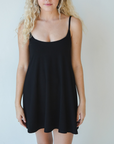 Product shot of NŪD Apparel Betty Swinging Slip Dress, thin adjustable strap, loose style and with shelf bra, made of bamboo fabric produced in California, in Black on fair-skinned model, front shot