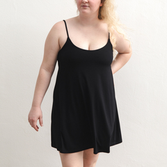 Product shot of NŪD Apparel Betty Swinging Slip Dress, thin adjustable strap, loose style and with shelf bra, made of bamboo fabric produced in California, in Black on fair-skinned model, front shot