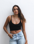 Product shot of NŪD Apparel Kyla Double Layered Crop top, thin strap and seamless, made of bamboo fabric produced in California, in Black on medium-skinned model paired with light-wash jeans, front shot