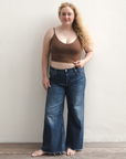 Product shot of NŪD Apparel Kyla Double Layered Crop top, thin strap and seamless, made of bamboo fabric produced in California, in Dark Nude on fair-skinned model paired with dark-wash jeans, front wide shot