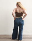 Product shot of NŪD Apparel Kyla Double Layered Crop top, thin strap and seamless, made of bamboo fabric produced in California, in Dark Nude on fair-skinned model paired with dark-wash jeans, back wide shot