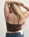 Product shot of NŪD Apparel Kyla Double Layered Crop top, thin strap and seamless, made of bamboo fabric produced in California, in Dark Nude on fair-skinned model paired with dark-wash jeans, back shot