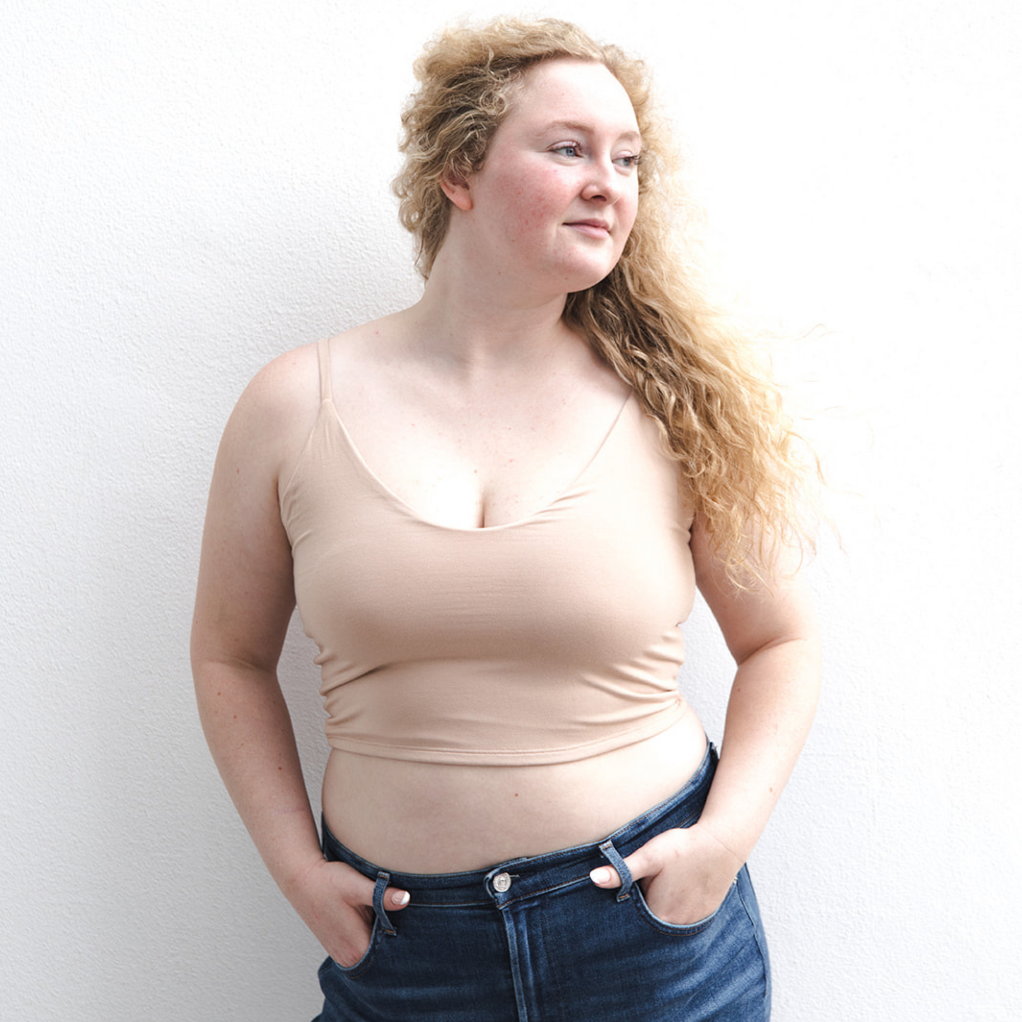 Product shot of NŪD Apparel Kyla Double Layered Crop top, thin strap and seamless, made of bamboo fabric produced in California, in Light Nude on fair-skinned model paired with dark-wash jeans, front shot