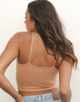 Product shot of NŪD Apparel Kyla Double Layered Crop top, thin strap and seamless, made of bamboo fabric produced in California, in Medium Nude on medium-skinned model paired with light-wash jeans, close-up back shot
