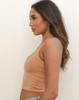 Product shot of NŪD Apparel Kyla Double Layered Crop top, thin strap and seamless, made of bamboo fabric produced in California, in Medium Nude on medium-skinned model paired with light-wash jeans, side shot