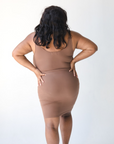 Product shot of NŪD Apparel Tayler Slip Dress, wide strap, fitted style and seamless, made of bamboo fabric produced in California, in Dark Nude on dark-skinned model, back shot