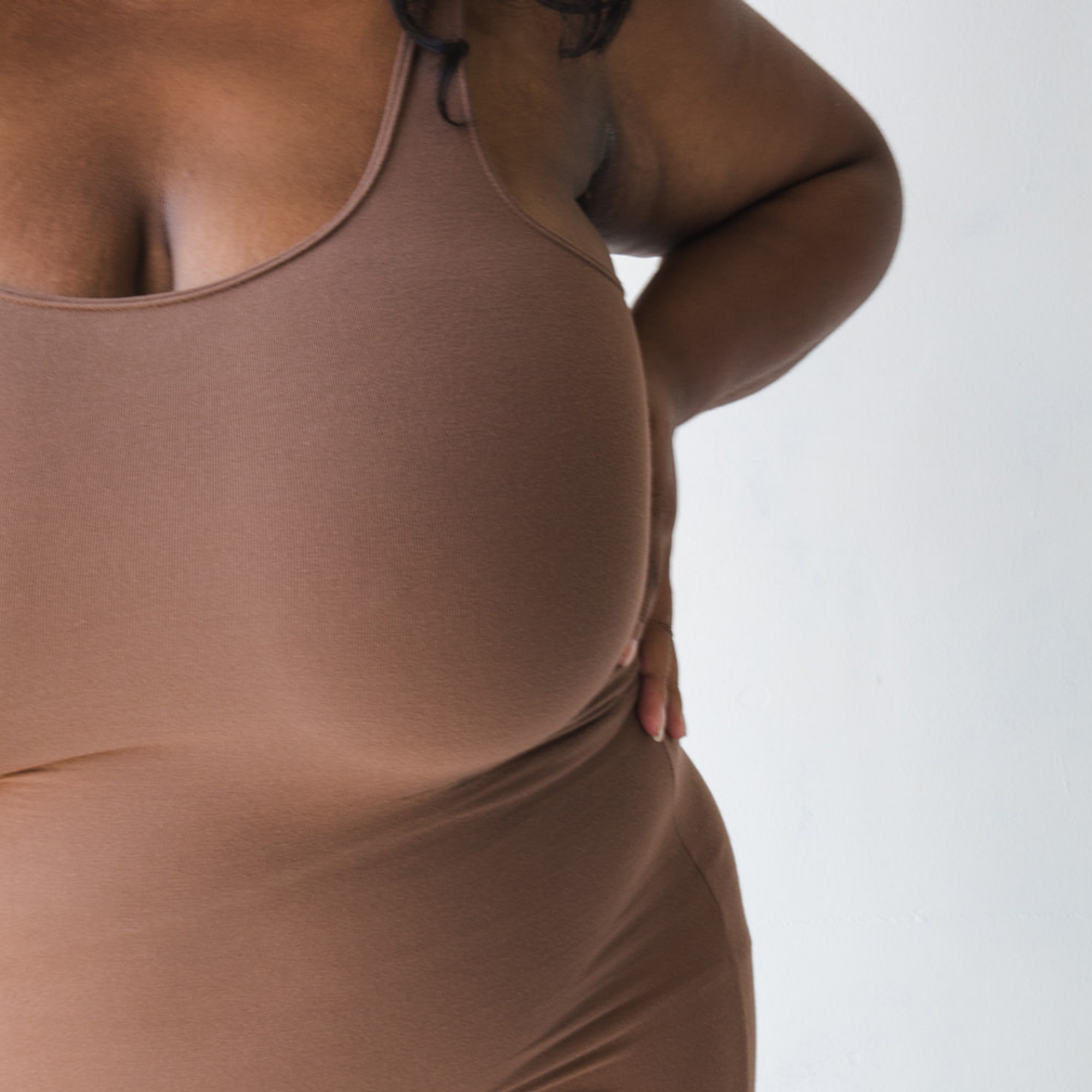 Product shot of NŪD Apparel Tayler Slip Dress, wide strap, fitted style and seamless, made of bamboo fabric produced in California, in Dark Nude on dark-skinned model, front close-up shot