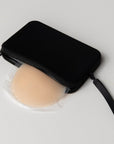 Product shot of our sticky Silicone Stick-on Bra in Light tint and our durable Silicone Travel Case in Black, showing the removable strap and zipper closure