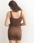 Product shot of NŪD Apparel Tayler Slip Dress, wide strap, fitted style and seamless, made of bamboo fabric produced in California, in Dark Nude on fair-skinned model, back shot