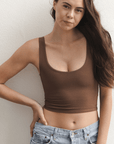 Product shot of NŪD Apparel Devon Double Layered Scoop Crop top, wide strap and seamless, made of bamboo fabric produced in California, in Dark Nude on fair-skinned model paired with light-wash jeans, front close-up shot
