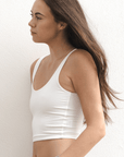 Product shot of NŪD Apparel Devon Double Layered Scoop Crop top, wide strap and seamless, made of bamboo fabric produced in California, in White on fair-skinned model paired with light-wash jeans, side shot