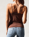 Product shot of NŪD Apparel Nesha Double Layered Tank, thin strap, long style and seamless, made of bamboo fabric produced in California, in Dark Nude on fair-skinned model paired with light-wash jeans, back shot