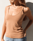 Product shot of NŪD Apparel Nesha Double Layered Tank, thin strap, long style and seamless, made of bamboo fabric produced in California, in Medium Nude on fair-skinned model paired with light-wash jeans, front shot