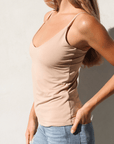 Product shot of NŪD Apparel Nesha Double Layered Tank, thin strap, long style and seamless, made of bamboo fabric produced in California, in Light Nude on fair-skinned model paired with light-wash jeans, front/side shot