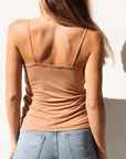 Product shot of NŪD Apparel Nesha Double Layered Tank, thin strap, long style and seamless, made of bamboo fabric produced in California, in Medium Nude on fair-skinned model paired with light-wash jeans, back shot