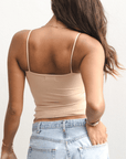Product shot of NŪD Apparel Nesha Double Layered Tank, thin strap, long style and seamless, made of bamboo fabric produced in California, in Light Nude on medium-skinned model paired with light-wash jeans, back shot