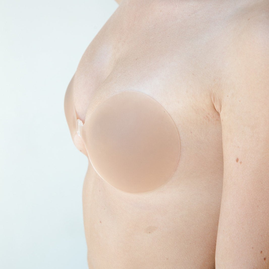Product shot Medium tint Silicone Stick-on Bra size C-cup on light-skinned model, close-up side shot of the Silicone Stick-on Bra showing the skin tint matches the model perfectly and the razor thin edges creating a seamless look