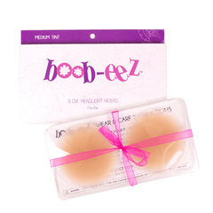 Product shot of reusable 8cm Medium tint Headlight Hiders in recycled craft packaging and informative insert card with wear and care instructions and Boob-eez brand story