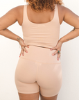 Product shot NŪD Apparel Zoë Biker Short, perfect length, no front seam and comfy, made of bamboo fabric produced in California, in Light Nude on medium-skinned model, paired with Devon Scoop Crop, back shot