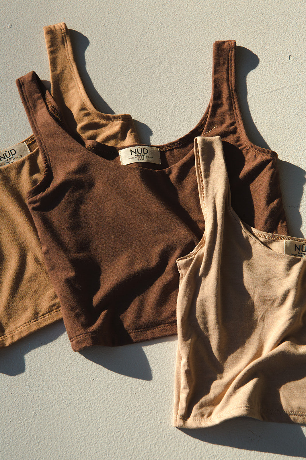 NŪD Apparel bamboo tank tops in dark and light nude shades, flat lay