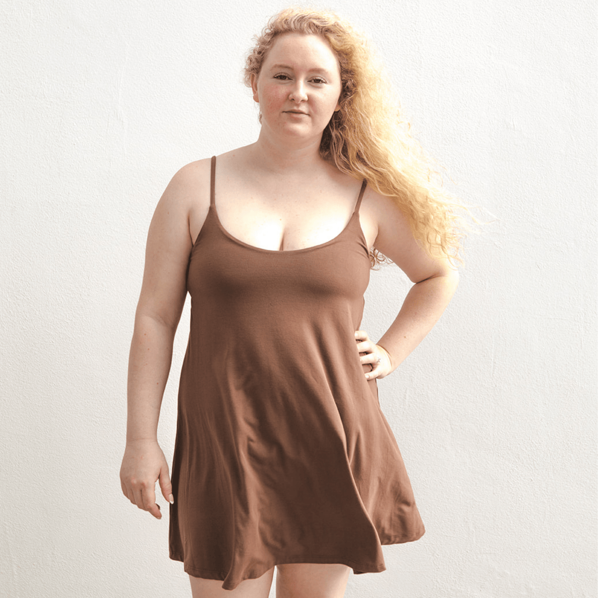 Product shot of NŪD Apparel Betty Swinging Slip Dress, thin adjustable strap, loose style and with shelf bra, made of bamboo fabric produced in California, in Dark Nude on fair-skinned model, front shot