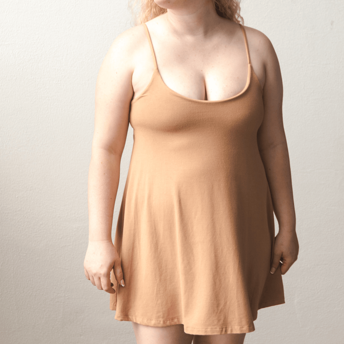 Product shot of NŪD Apparel Betty Swinging Slip Dress, thin adjustable strap, loose style and with shelf bra, made of bamboo fabric produced in California, in Medium Nude on fair-skinned model, front shot