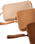 Product shot of durable Silicone Travel Cases for Silicone Stick-on Bra in Light Nude, Medium Nude, and Dark Nude, against a white background showing the Boob-eez branded detail and removable strap