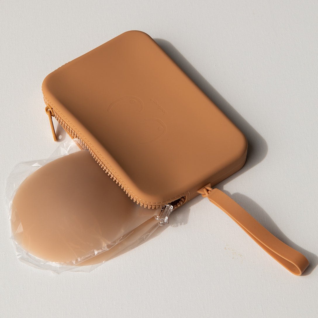 Product shot of our sticky Silicone Stick-on Bra in Medium tint and a durable Silicone Travel Case for the Silicone Stick-on Bra in Medium Nude, close-up shot showing the Boob-eez branded case and removable strap