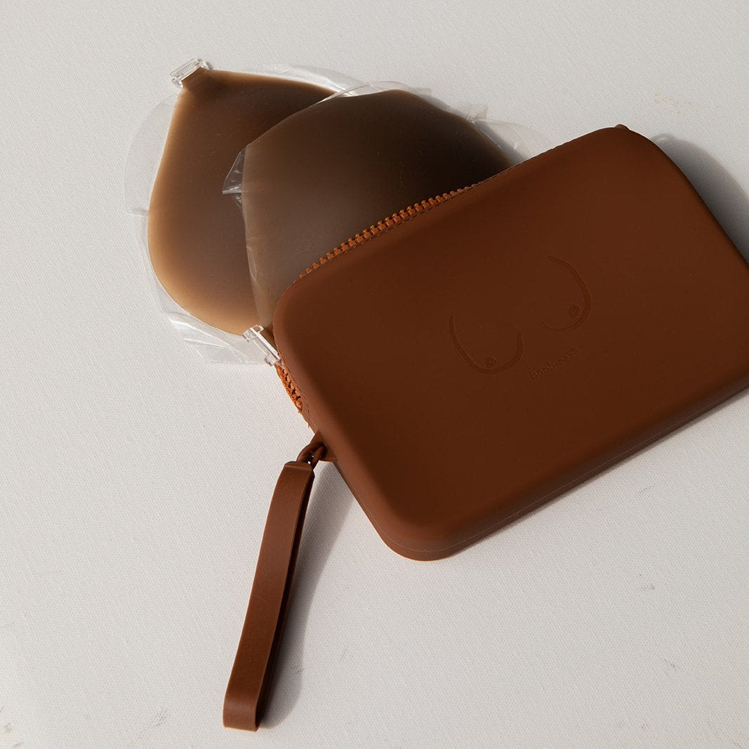 Product shot of our stick Silicone Stick-on Bra and our durable Silicone Travel Case for the Silicone Stick-on Bra in Dark Nude, close-up shot showing the Boob-eez branded case and removable strap