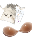 Product shot of reusable and sticky Medium Tint Silicone Stick-on Bra with a branded drawstring unbleached cotton muslin pouch packaging and information insert card with wear and care instructions, showing thin edge of the Silicone Stick-on Bra