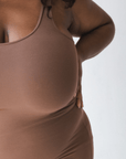 Product shot of NŪD Apparel Tayler Slip Dress, wide strap, fitted style and seamless, made of bamboo fabric produced in California, in Dark Nude on dark-skinned model, front close-up shot