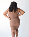 Product shot of NŪD Apparel Tayler Slip Dress, wide strap, fitted style and seamless, made of bamboo fabric produced in California, in Dark Nude on dark-skinned model, back shot